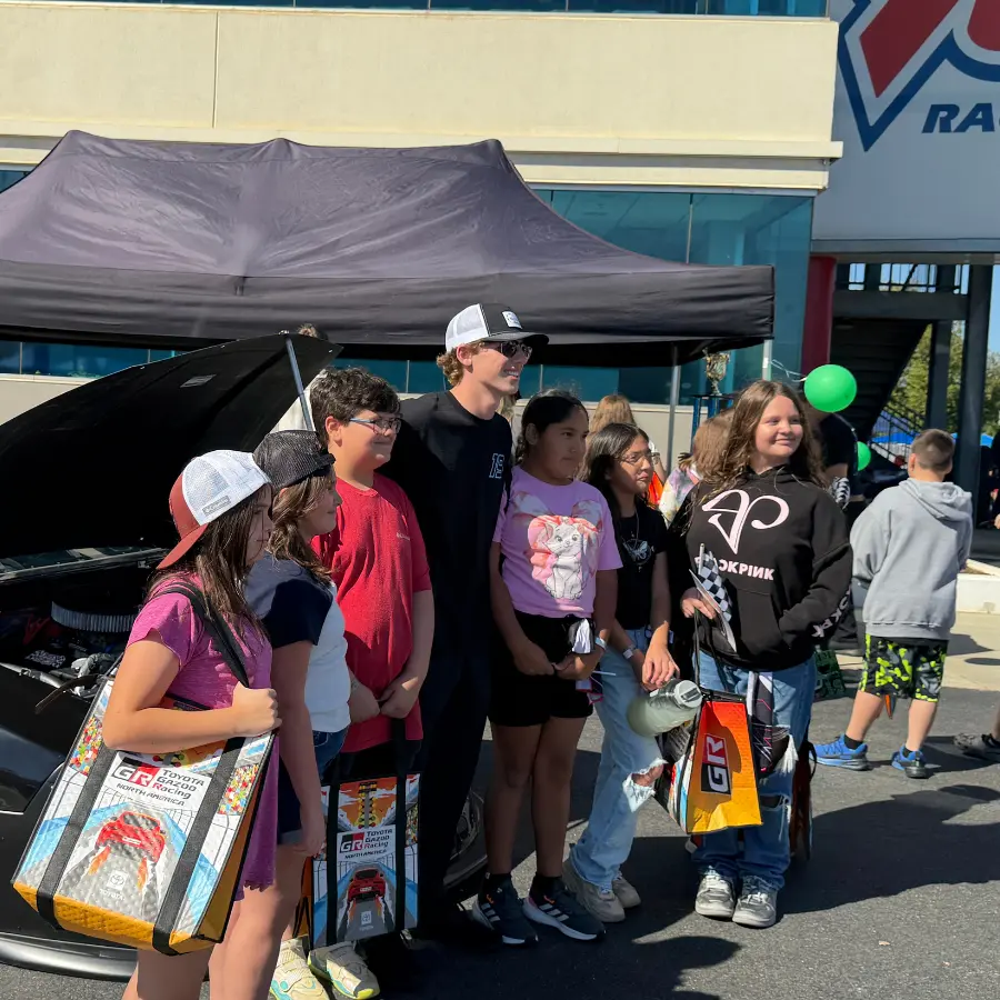Group photo with families at a trackside partner activation.