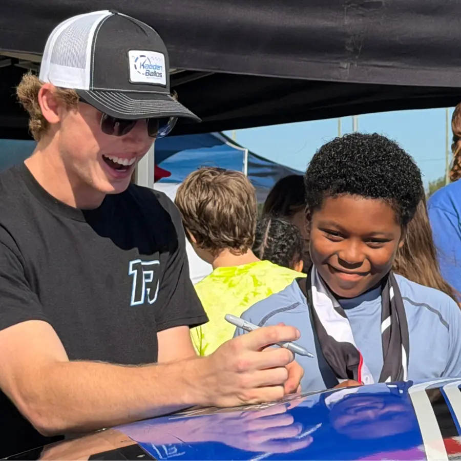 Kaeden Ballos signing autographs for kids at a community event.