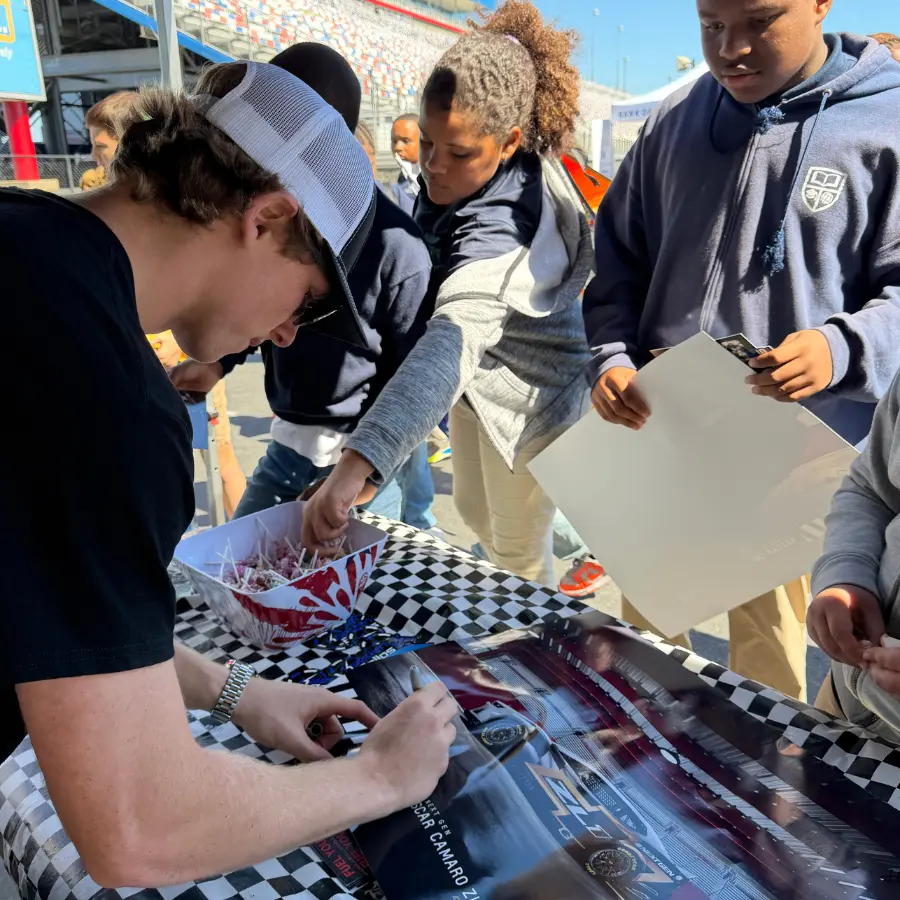 Kaeden signing hero cards at an appearance table.