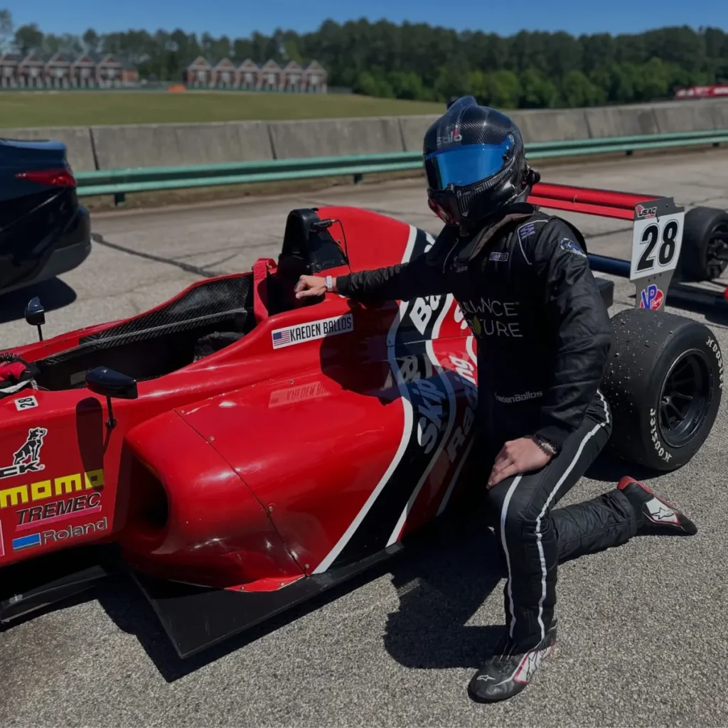 Kaeden Ballos kneeling by a Skip Barber car
